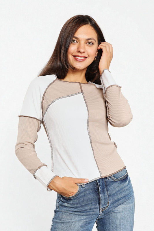 Woman wearing a color-blocked long-sleeve top and jeans on a white background