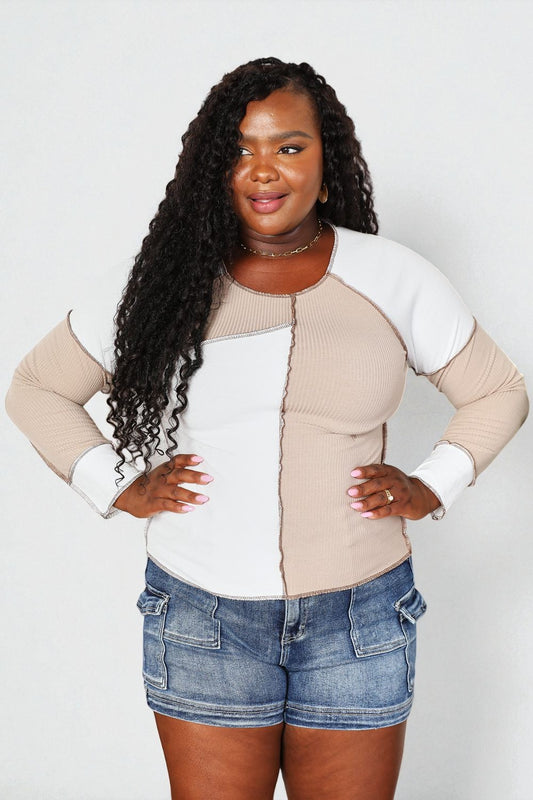 Woman wearing a beige and white long-sleeve top with denim shorts on a plain background