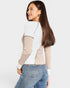 Woman wearing a two-tone top and jeans on a white background
