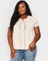 Woman wearing a beige top with lace details and blue jeans on a white background