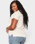 Woman wearing a beige top and blue jeans on a white background