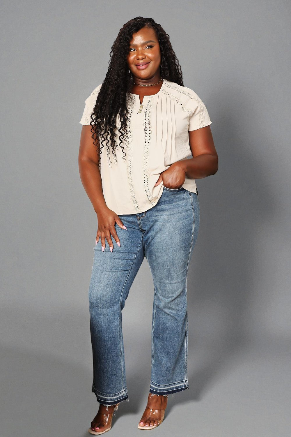 Woman wearing a white blouse and blue jeans against a gray background