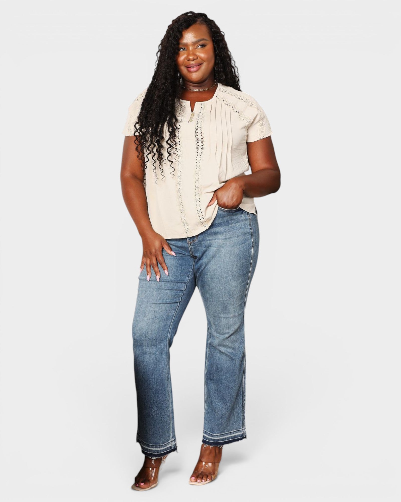 Woman wearing a beige top and blue jeans on a white background
