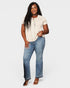 Woman wearing a beige top and blue jeans on a white background