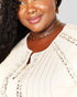 Woman wearing a beige lace top with gold jewelry on a white background