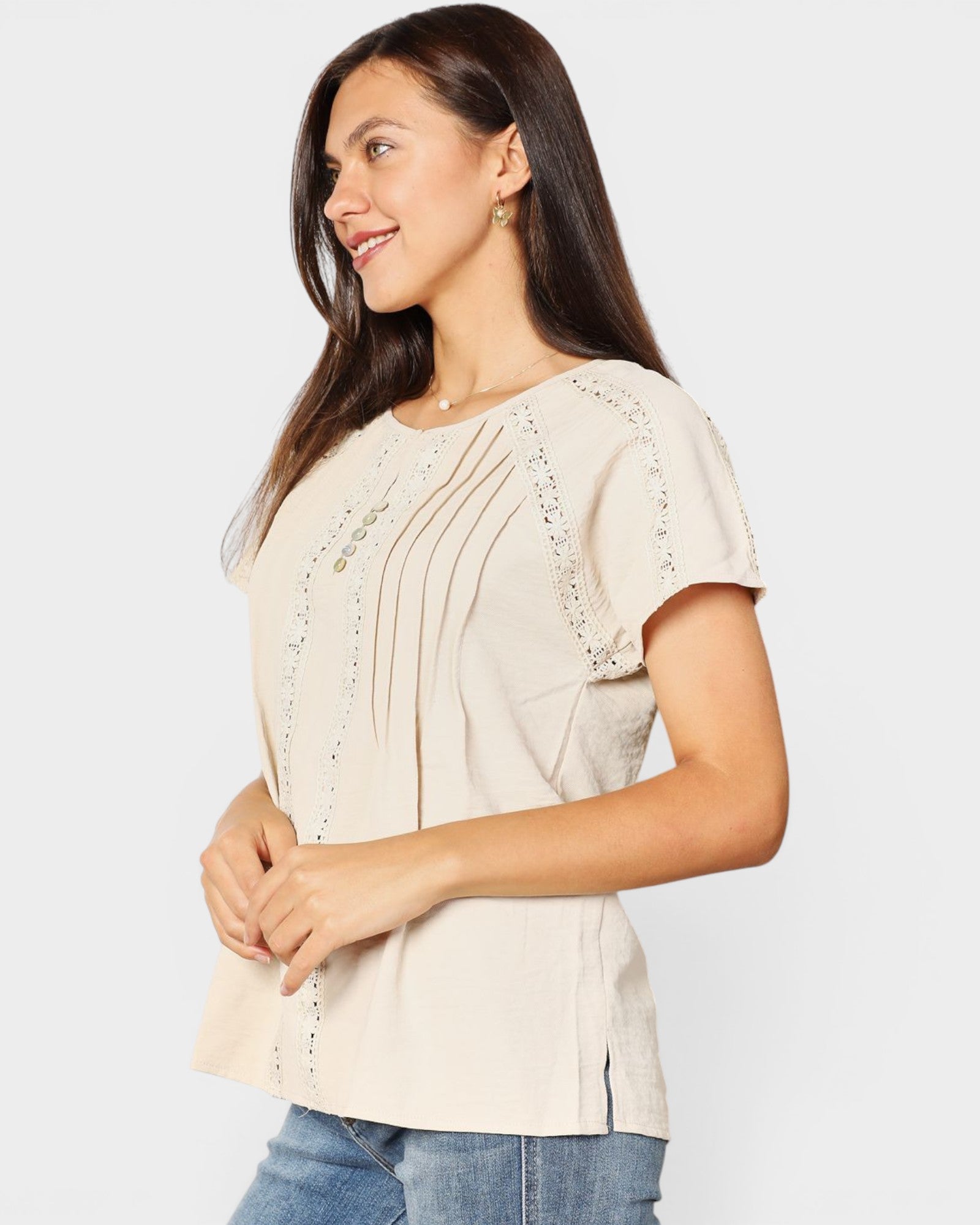 Woman wearing a beige blouse with lace details on a white background
