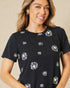 Woman wearing a black t-shirt with white floral patterns on a beige background