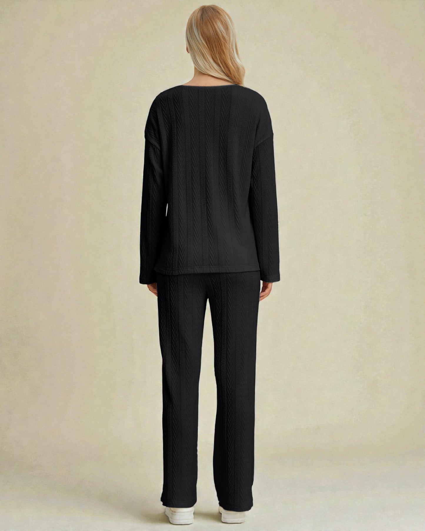 Person wearing a black outfit against a beige background