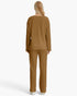 A woman viewed from the back wearing a matching ribbed knit two-piece set in a warm camel brown color, consisting of a long-sleeve top and wide-leg pants, against a plain white background.