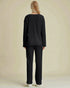 Person wearing a black outfit against a beige background