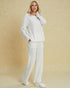 Woman wearing a white outfit against a beige background