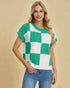 Woman wearing a green and white checkered sweater against a beige background