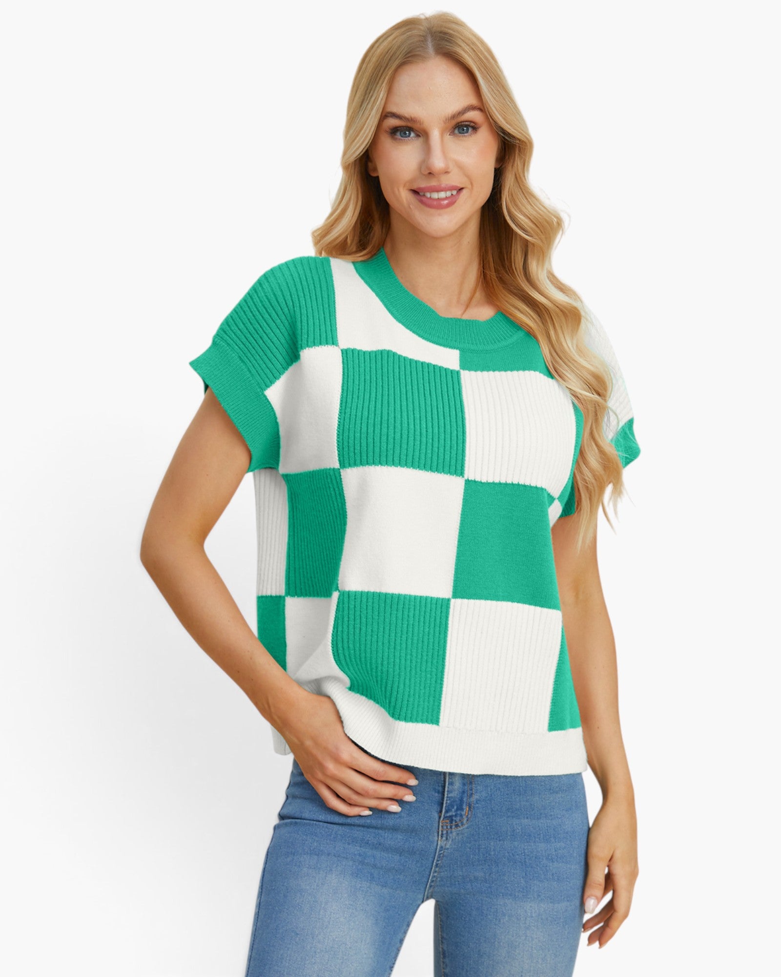 A woman modeling a short-sleeve knit top with a green and white checkerboard pattern, paired with blue jeans, against a plain white studio background.