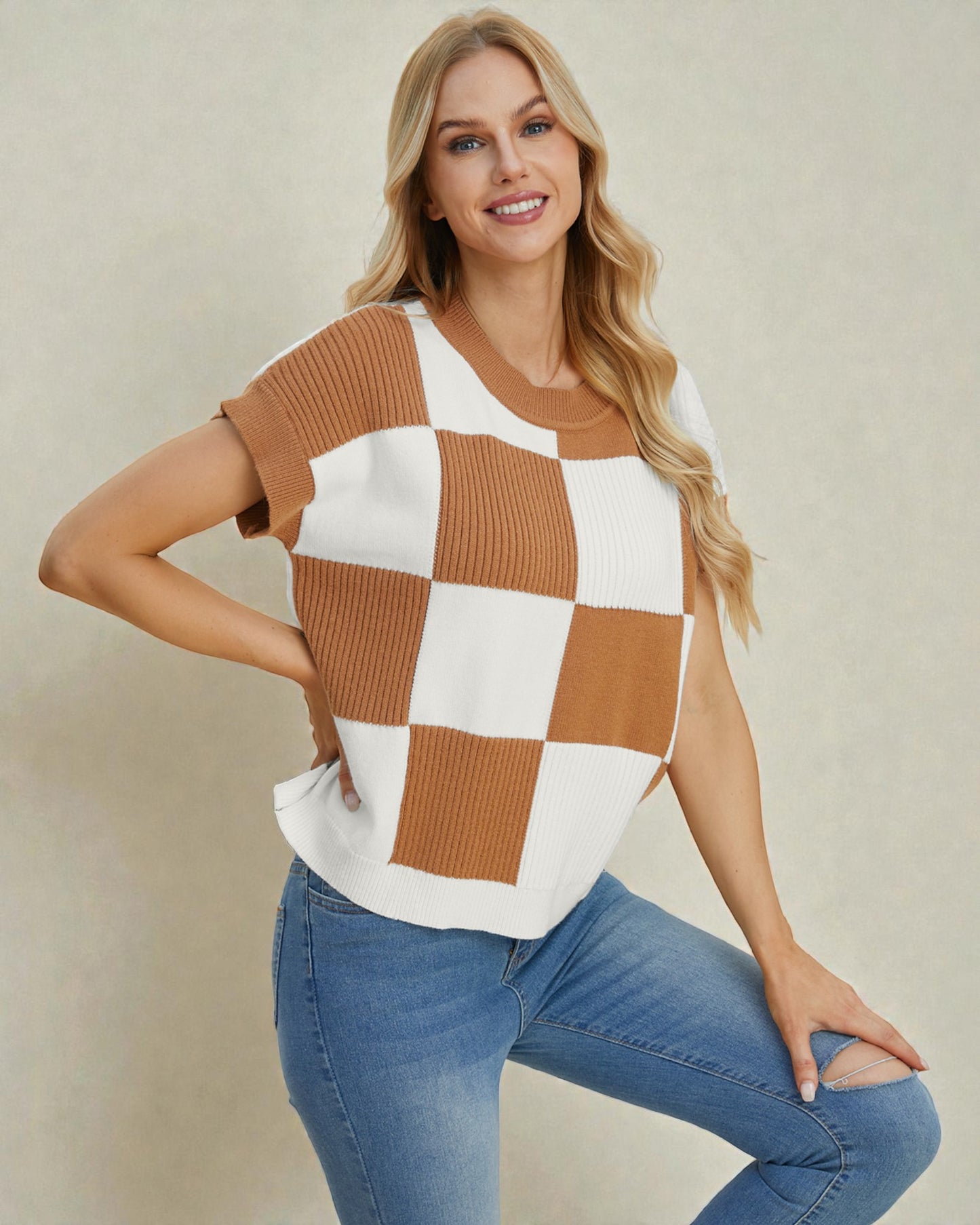 Woman wearing a checkered top and jeans against a plain background
