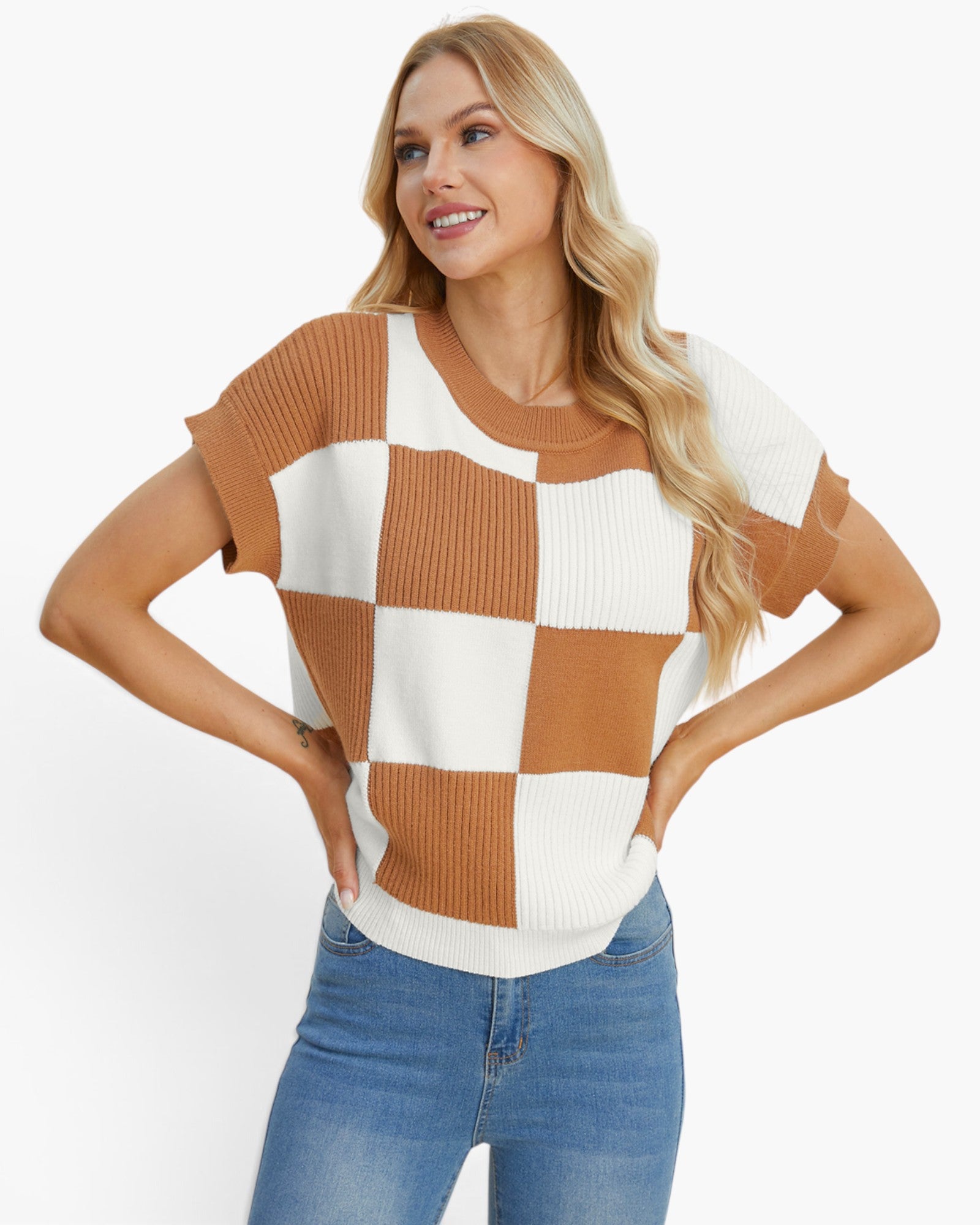 A woman modeling a short-sleeve knit top with a brown and off-white checkerboard pattern, paired with blue jeans, against a plain white background.