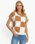 A woman modeling a short-sleeve knit top with a brown and white checkered pattern, paired with blue jeans, against a plain white background.