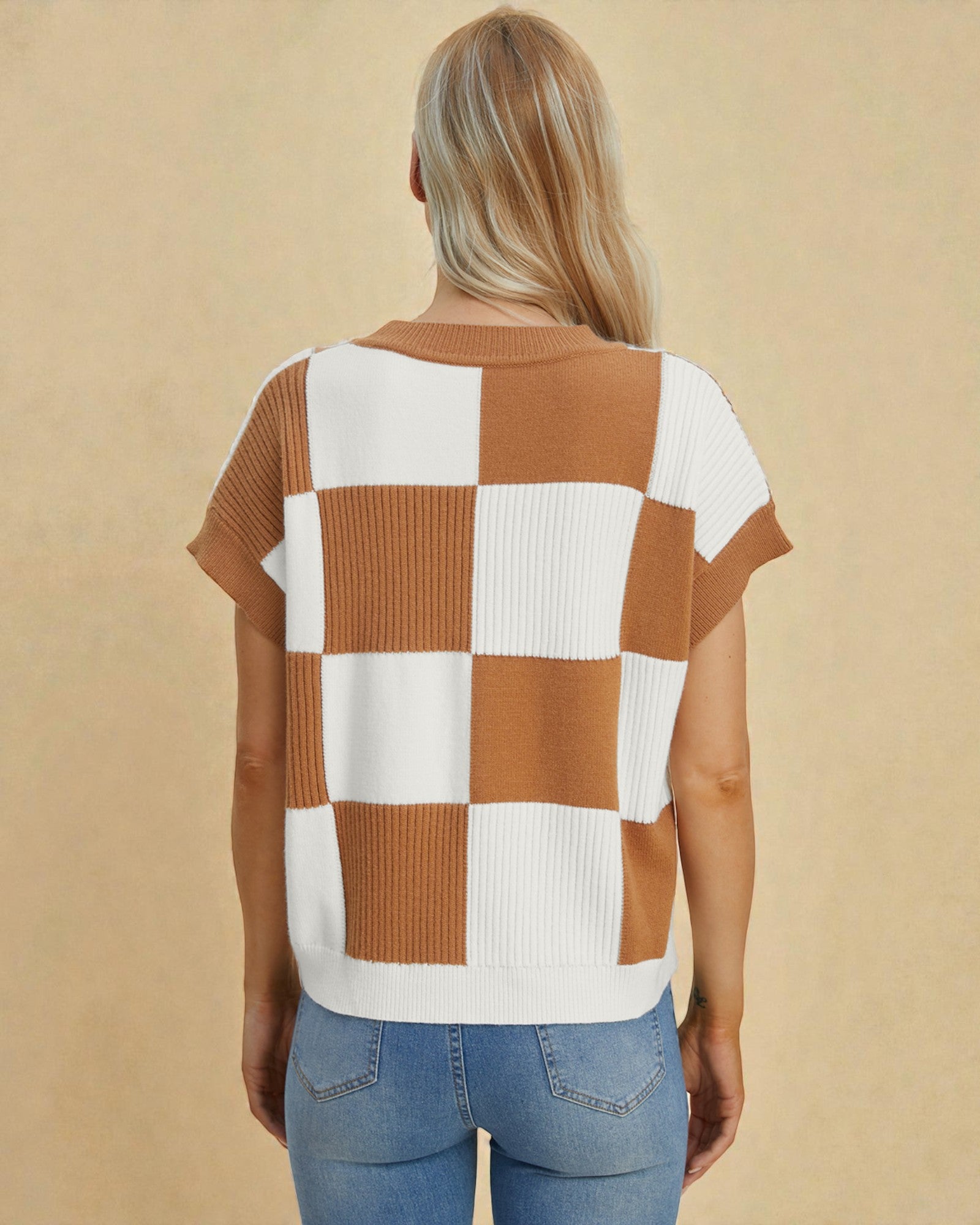Person wearing a checkered brown and white top with blue jeans on a beige background