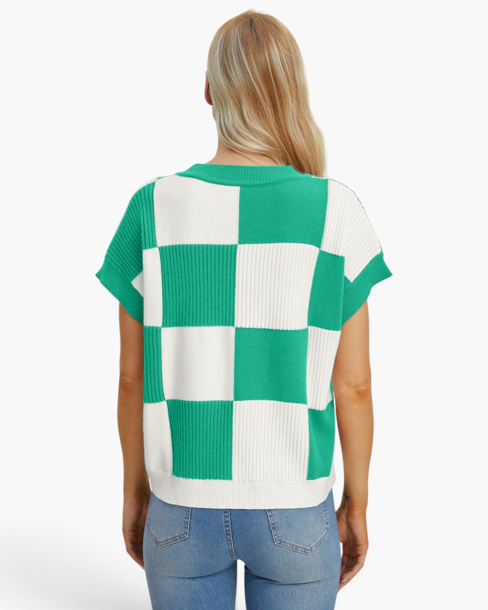 A woman viewed from behind wearing a green and white checkered short-sleeve knit top and blue jeans against a plain white studio background.