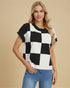 Woman wearing a black and white checkered sweater with blue jeans on a beige background