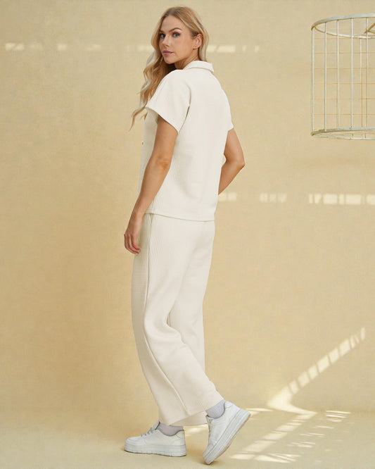 Woman wearing a white outfit standing against a beige wall