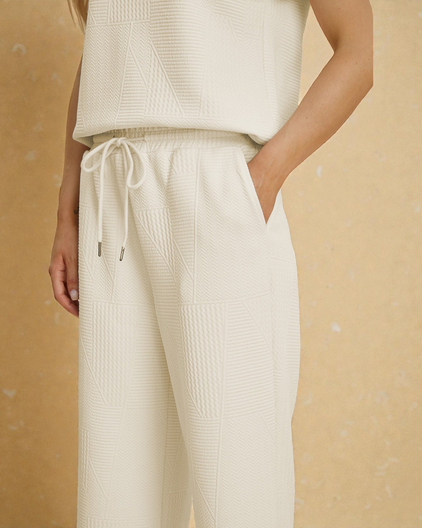 Person wearing a cream-colored knit outfit on a beige background