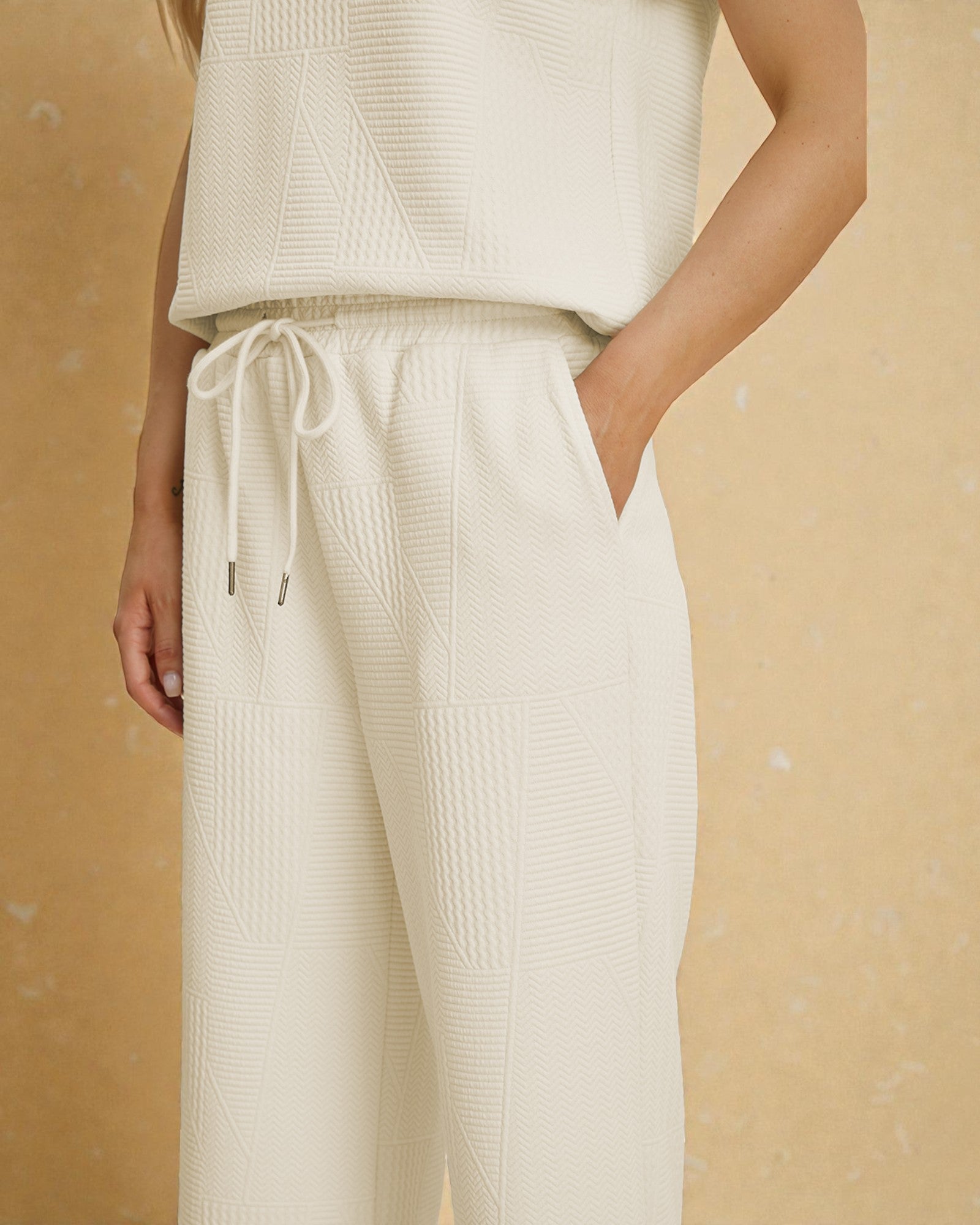 Person wearing a cream-colored knit outfit on a beige background