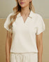 Woman wearing a white textured top against a beige background