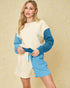 Woman wearing a cream and blue outfit against a beige background