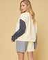 Woman wearing a cream and gray sweater with a beige background