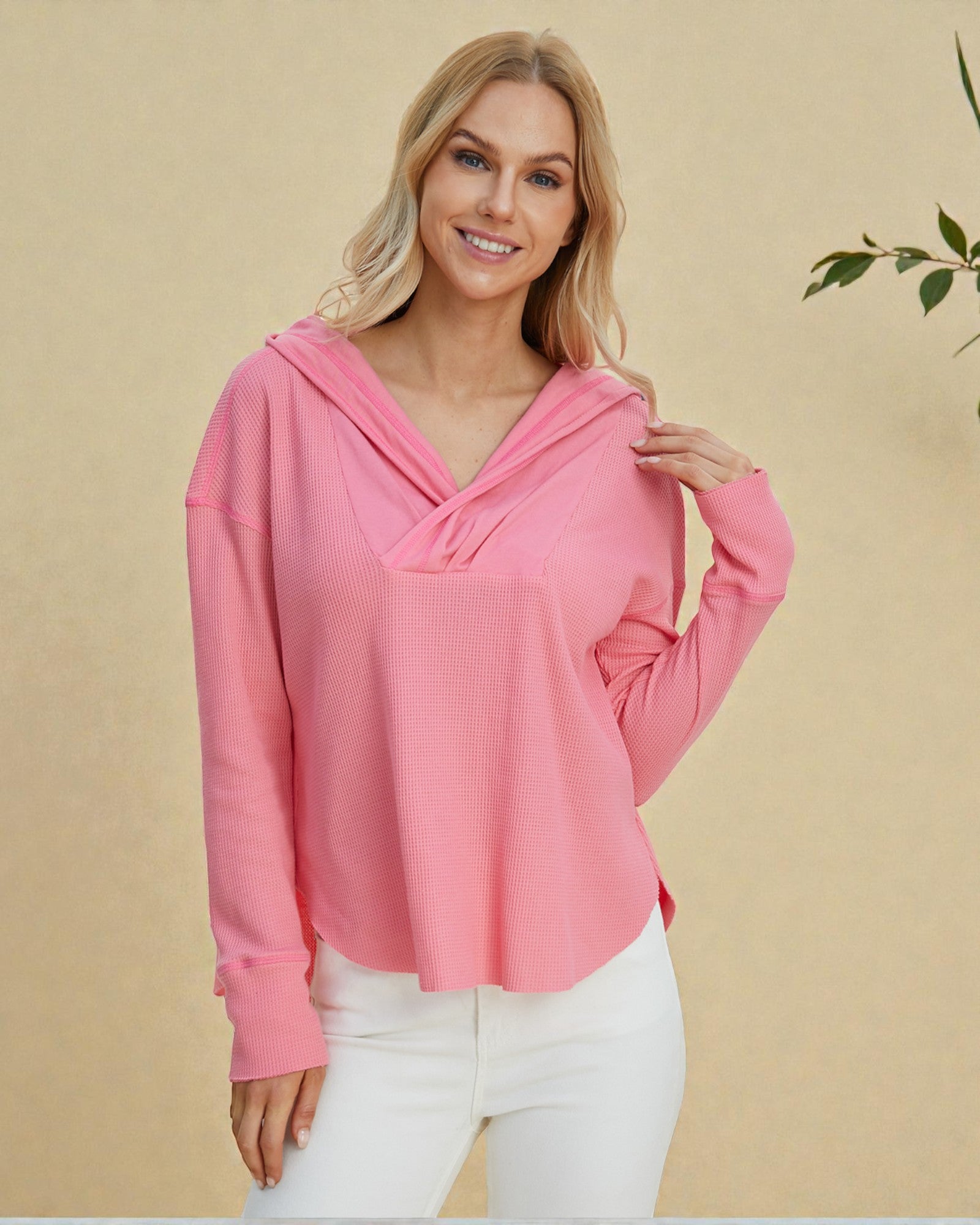 Woman wearing a pink long-sleeve top with a beige background