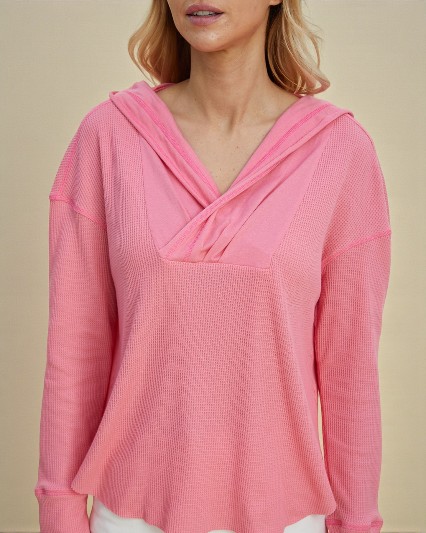 Pink hooded top worn by a person on a beige background