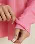Close-up of a person wearing a pink textured garment with rolled-up sleeves.