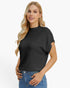 A blonde woman wearing a black short-sleeve mock neck knit top with ribbed sleeve cuffs, paired with blue jeans, against a plain white background.