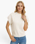 A woman modeling a cream-colored short-sleeve knit sweater with ribbed trim, paired with blue jeans, against a plain white background.