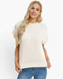 A woman wearing a cream-colored short-sleeve knit sweater with ribbed trim, paired with blue jeans, against a plain white background.