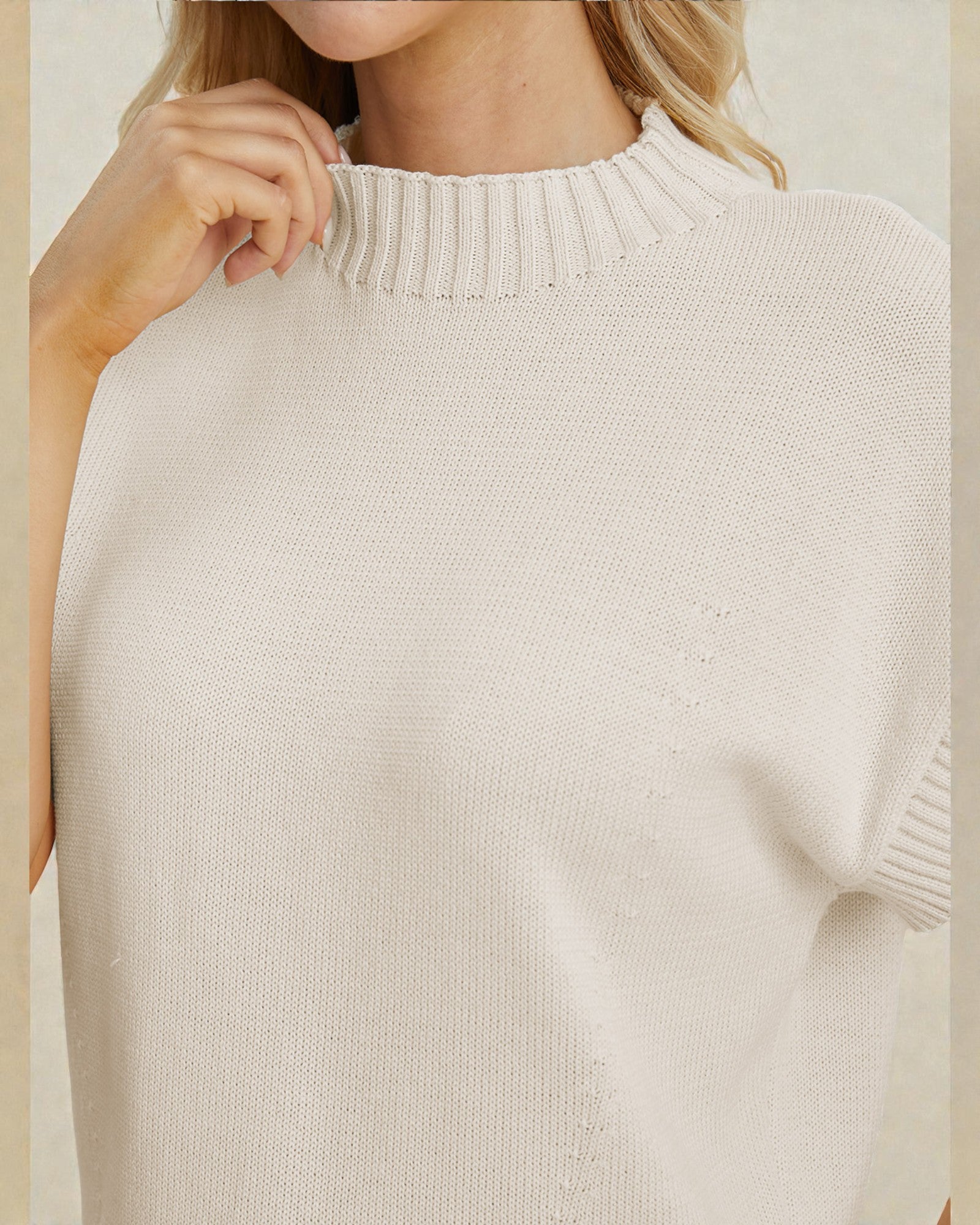 Close-up of a person wearing a beige sweater against a neutral background