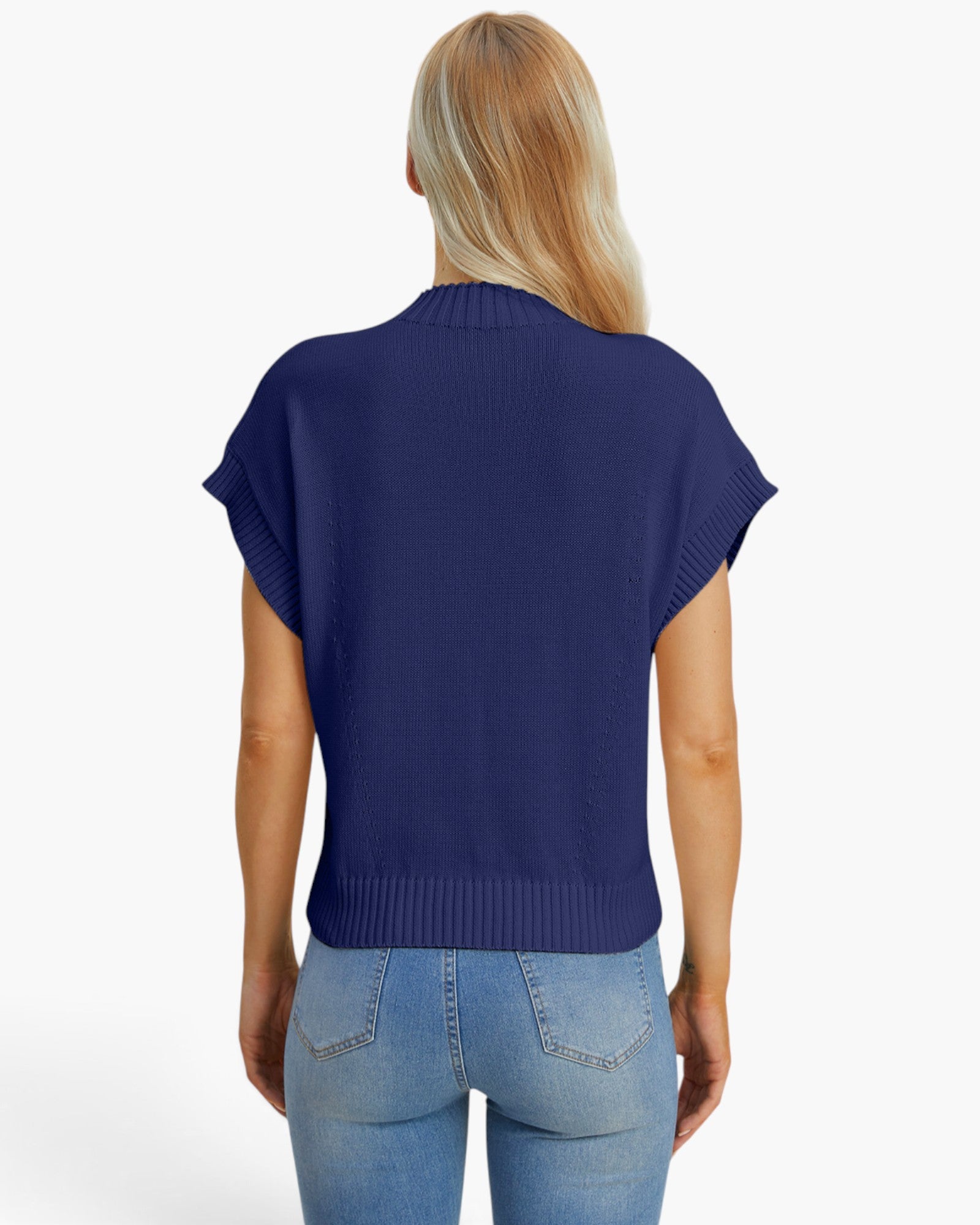 A woman viewed from the back wearing a navy blue short-sleeve ribbed knit top and light blue jeans against a plain white studio background.