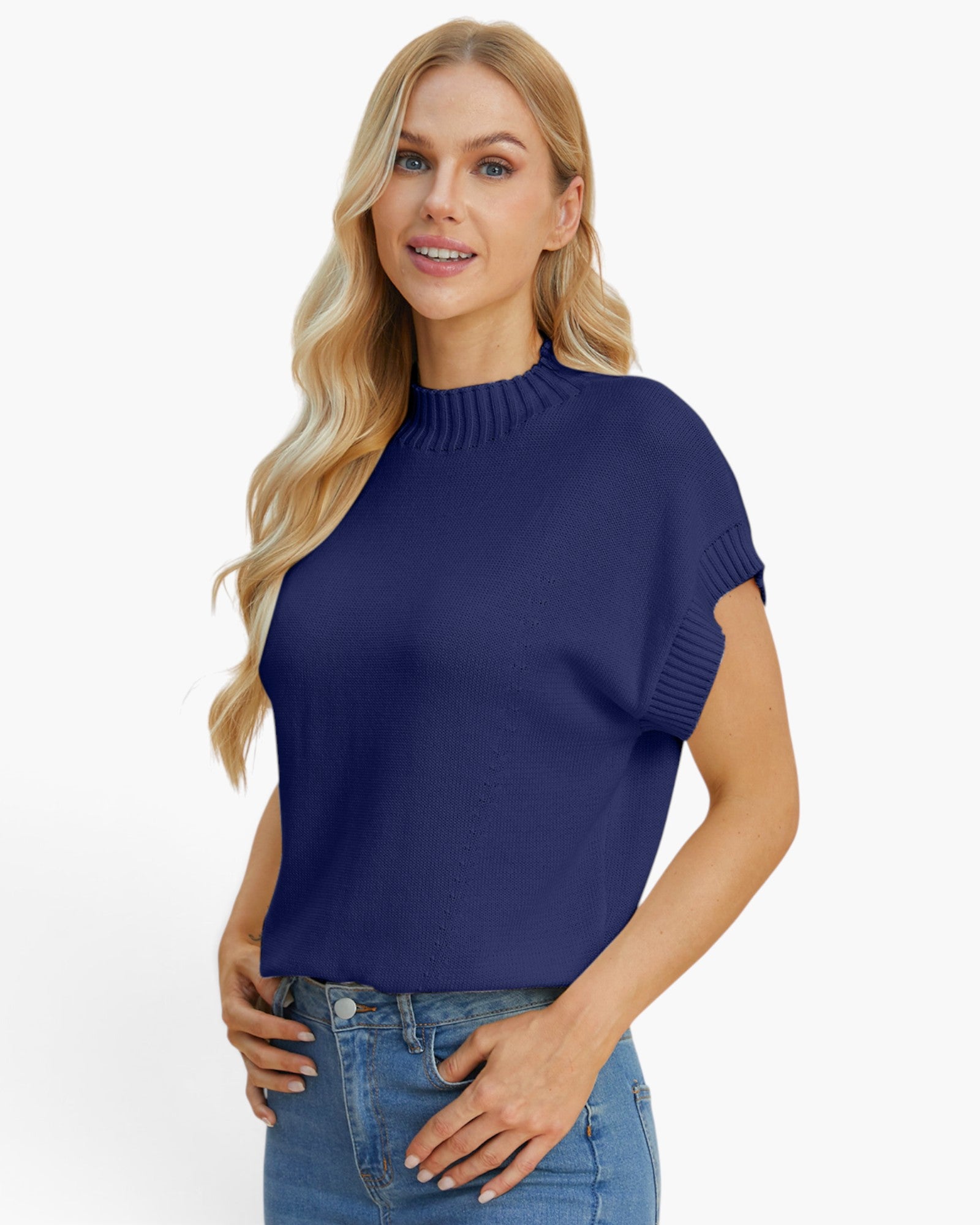A blonde woman wearing a navy blue short-sleeve mock neck knit top and blue jeans, posing against a solid white studio background.
