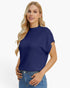 A blonde woman wearing a navy blue short-sleeve mock neck knit top and blue jeans, posing against a solid white studio background.