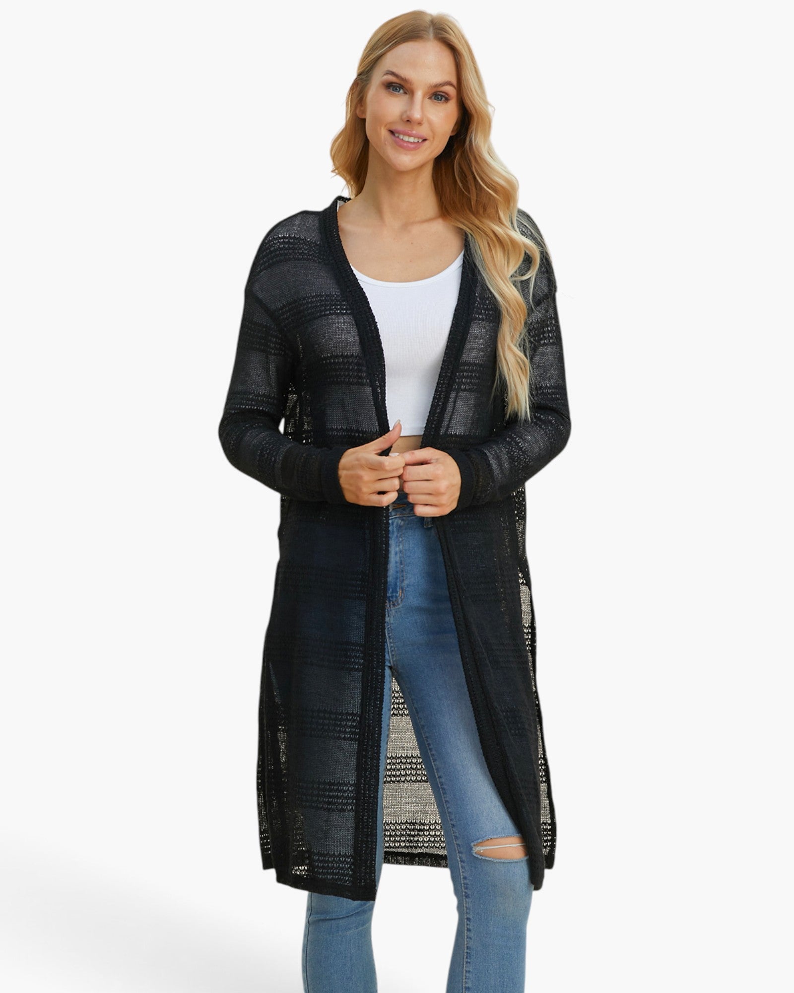 A woman modeling a long black open-front cardigan with a textured knit pattern, worn over a white tank top and blue jeans, against a plain white studio background.