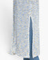 Close-up of a textured knit cardigan with a vertical front slit, featuring a marled pattern of light blue, white, and yellow, worn over blue jeans.