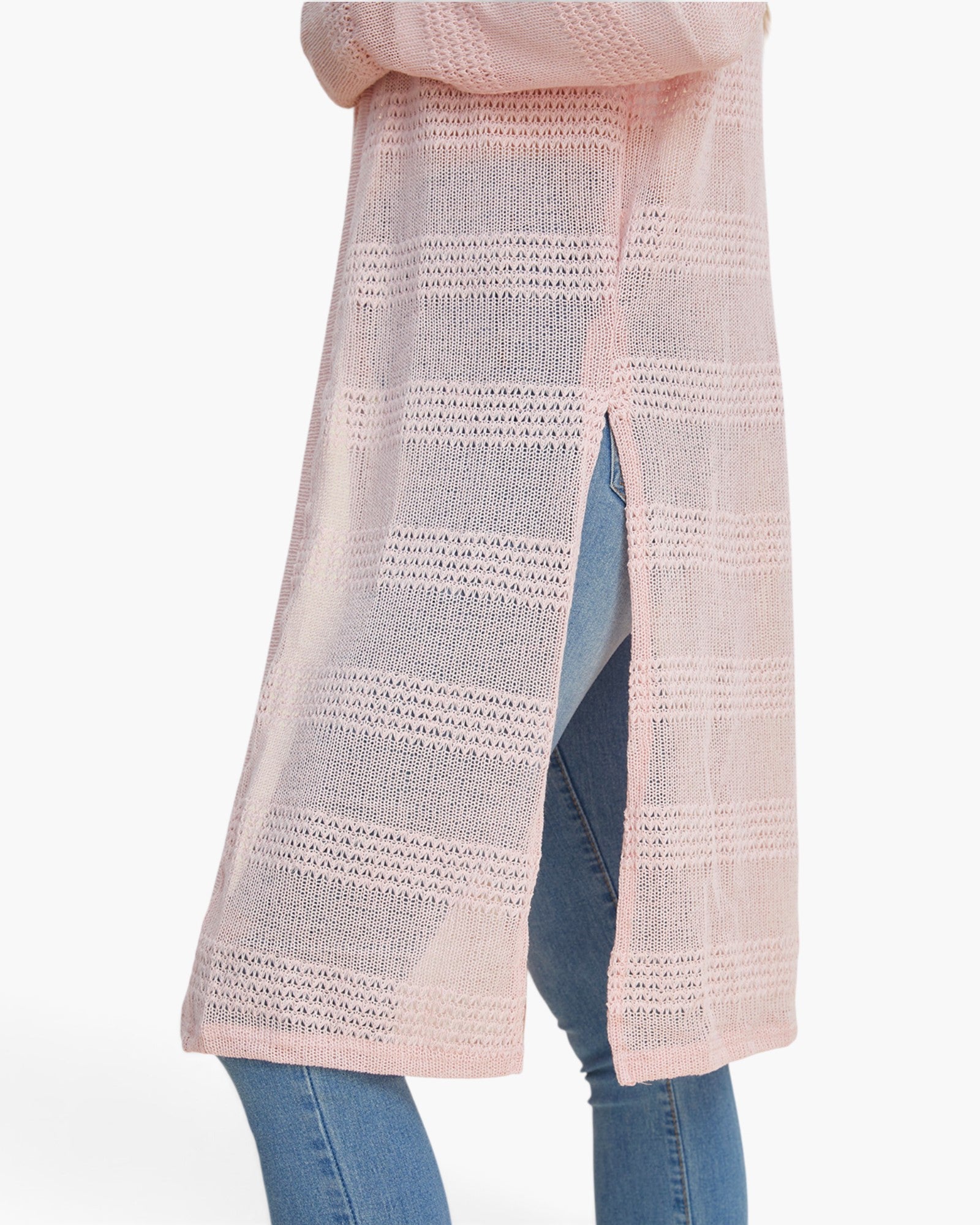 A light pink open-knit cardigan with horizontal textured stripes, shown worn over blue jeans against a plain white background.