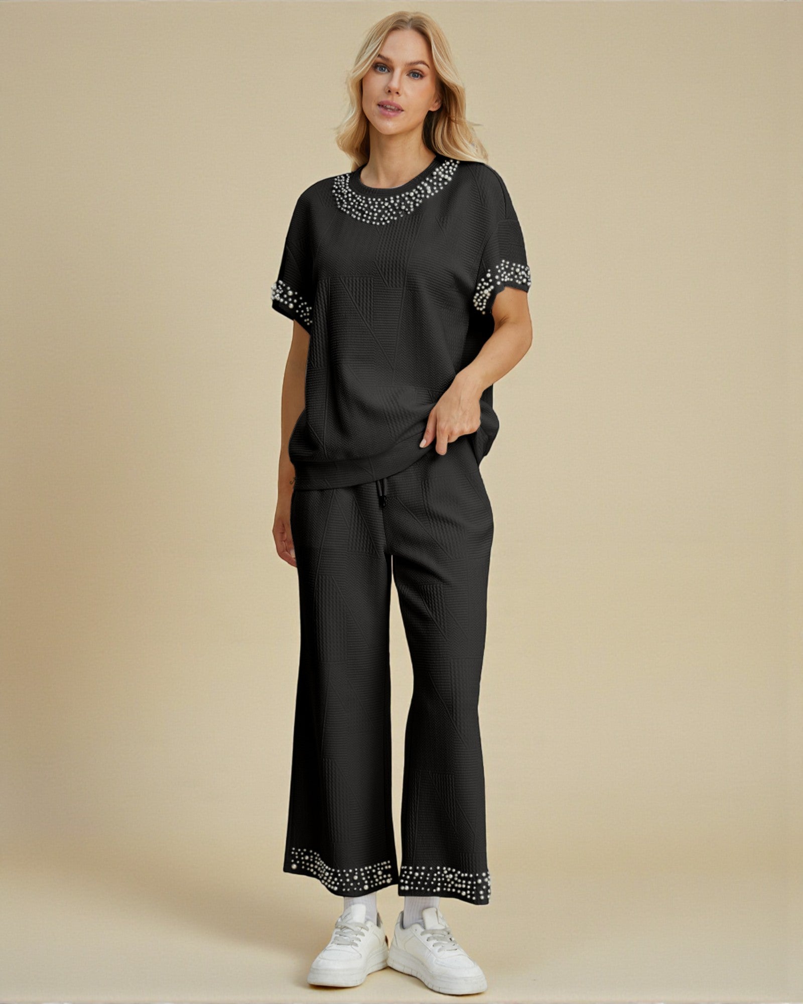 Woman wearing a black outfit with white embroidery on a beige background