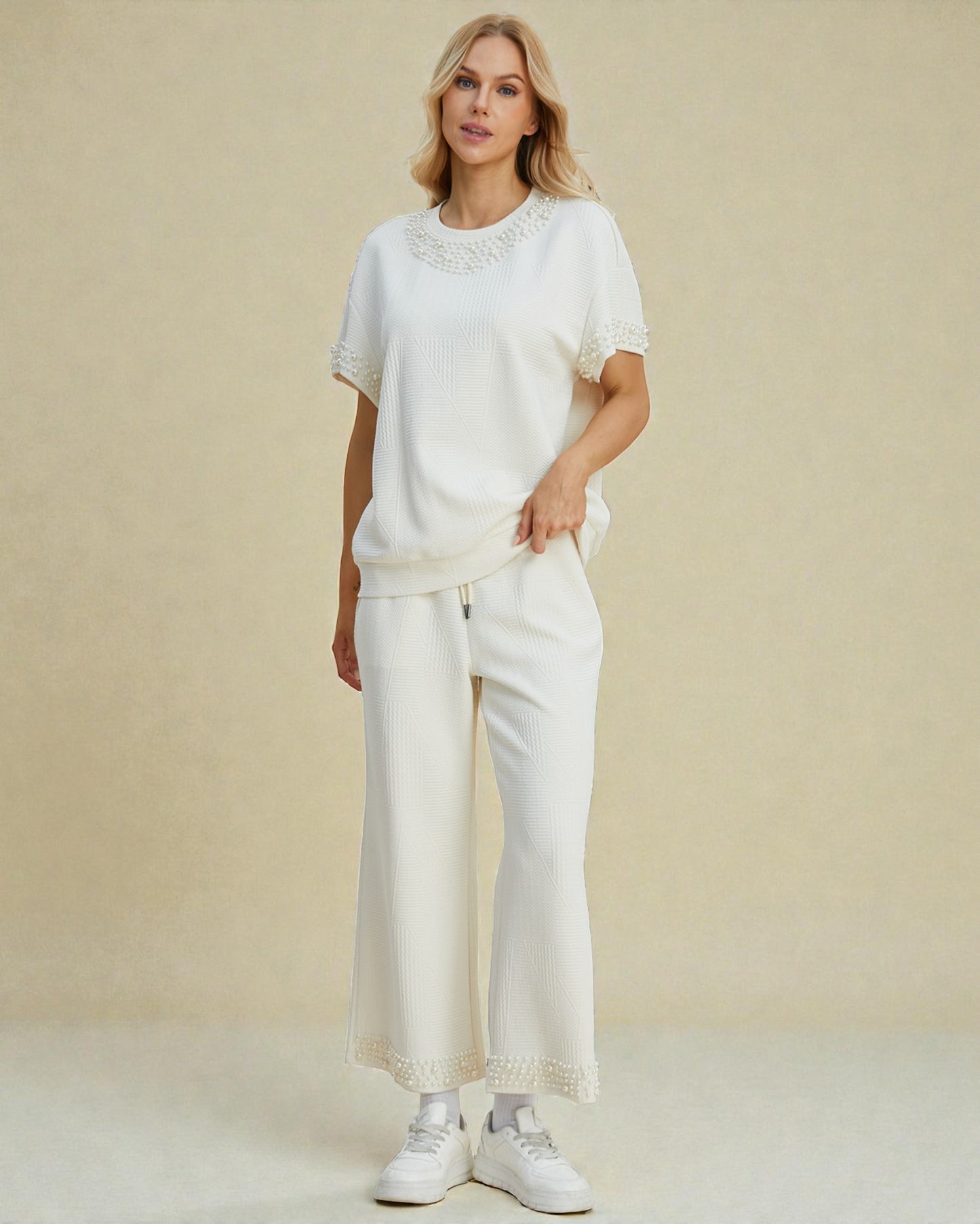 Woman wearing a white outfit with lace details on a beige background