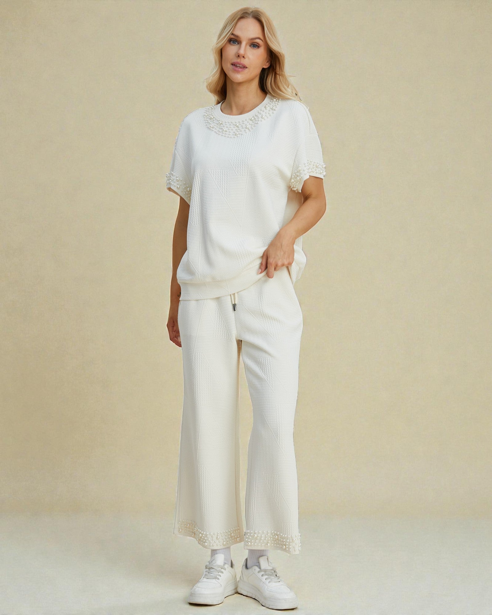 Woman wearing a white outfit with lace details on a beige background