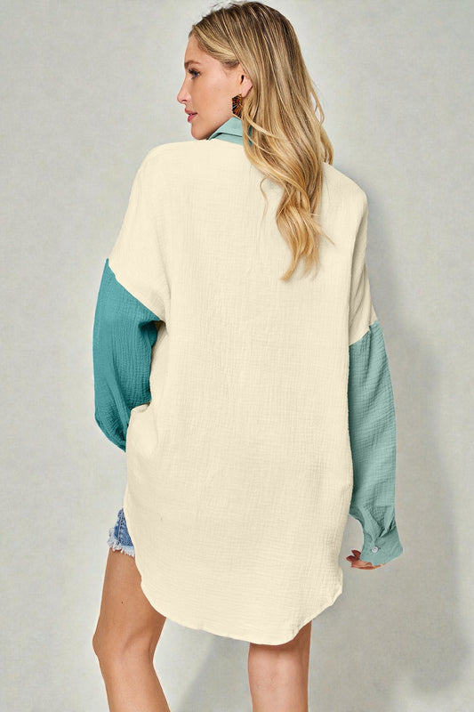 Woman wearing a cream and teal color-blocked sweater against a gray background