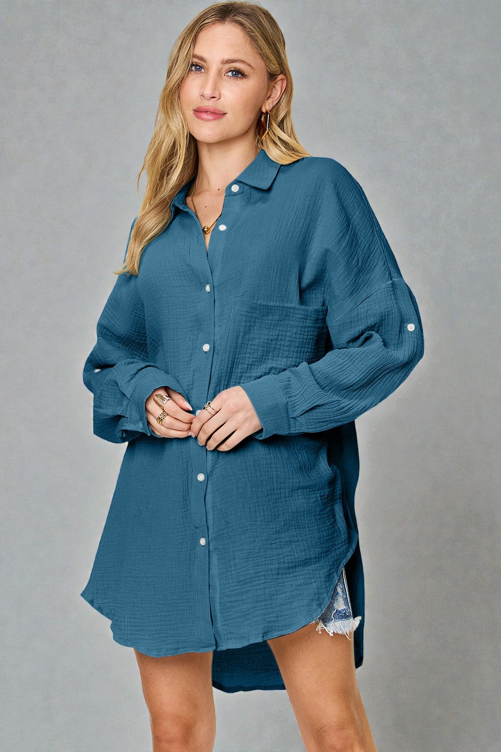 Woman wearing a blue button-up shirt over a denim skirt on a gray background