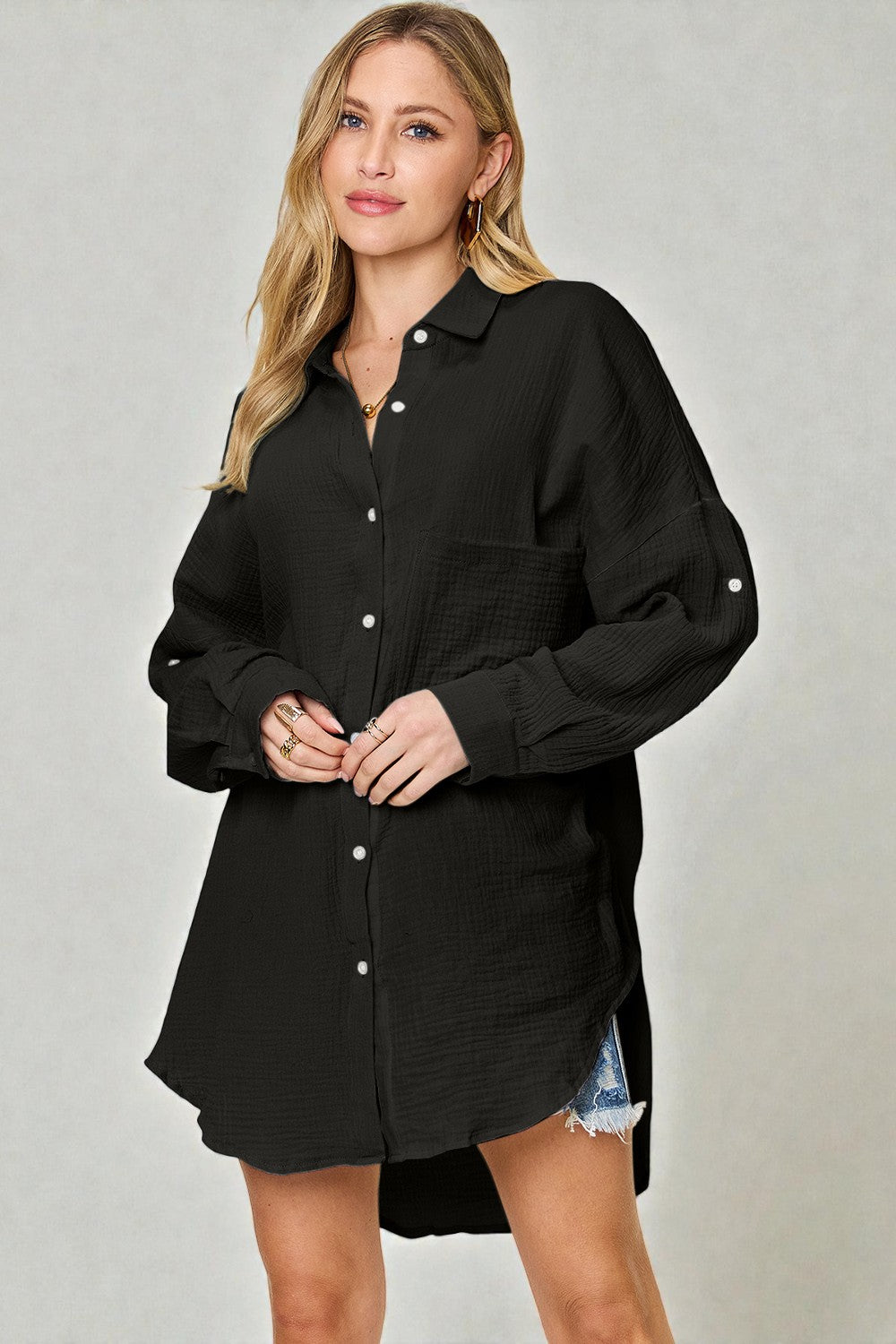 Woman wearing a black button-up shirt dress against a plain background