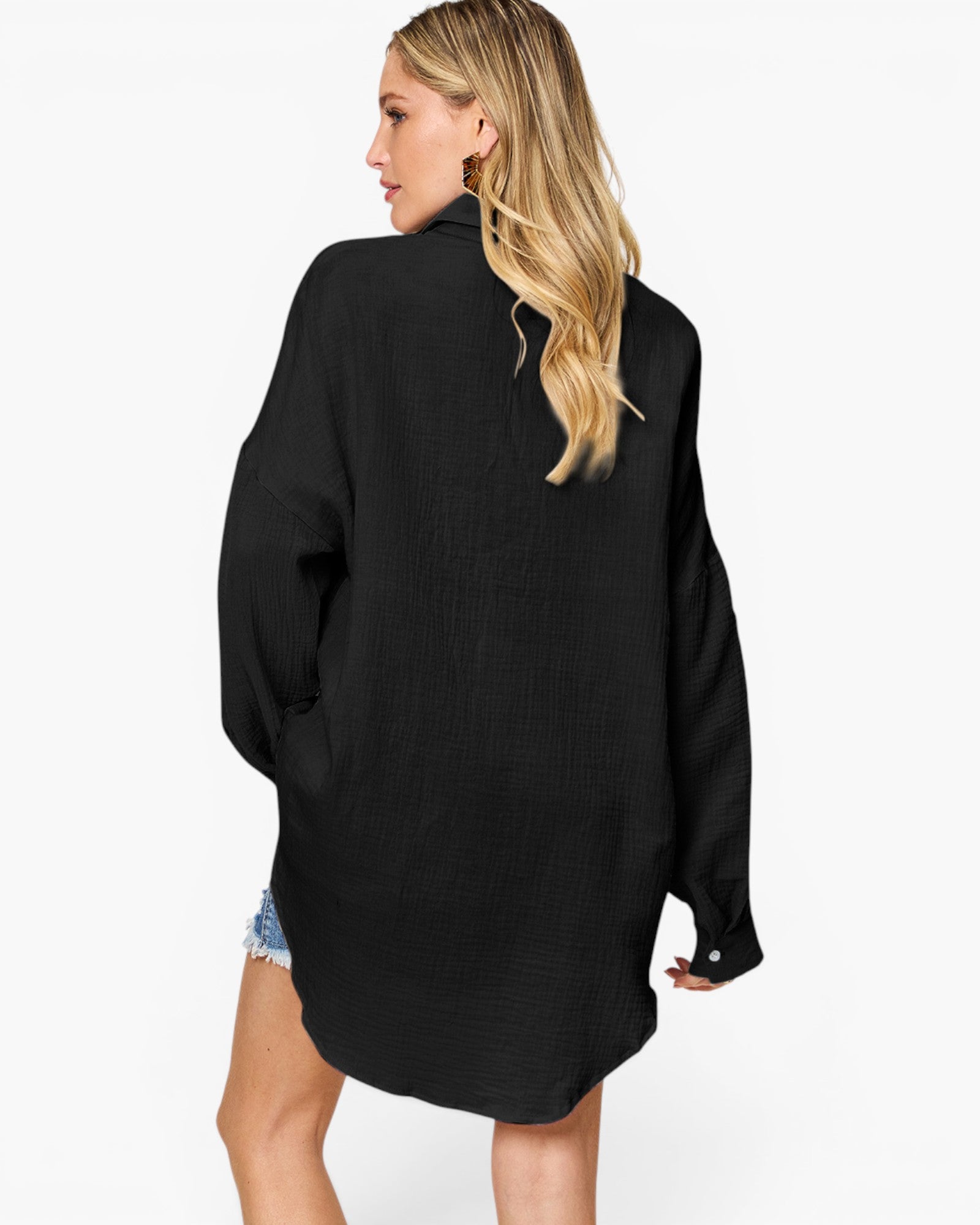 A woman shown from the back wearing an oversized black textured long-sleeve shirt dress, paired with denim shorts, against a plain white background.