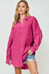 Woman wearing a bright pink shirt over denim shorts on a white background